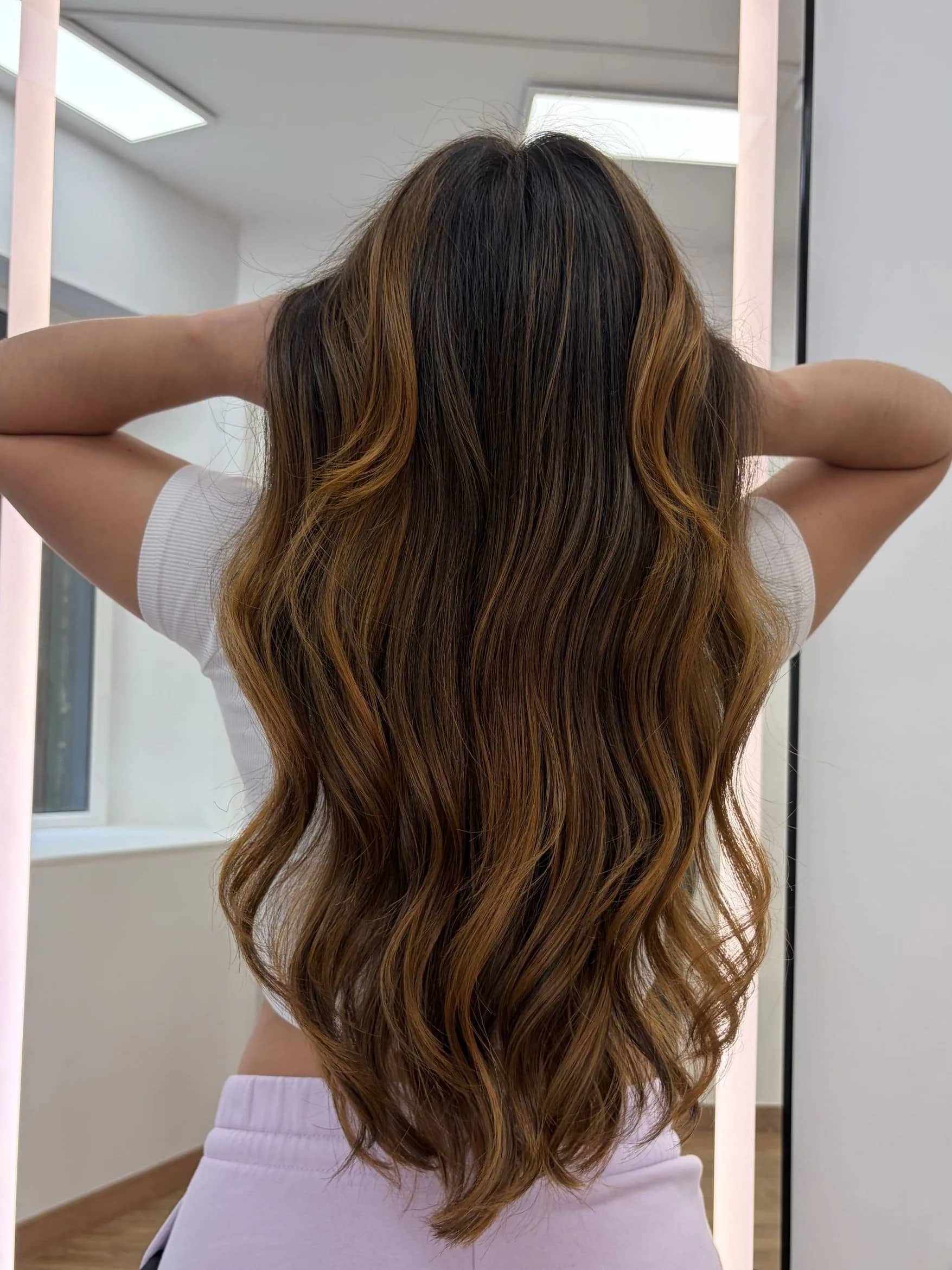Balayage caramelo en melena castaña larga con ondas naturales en Barcelona